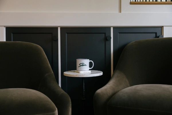 Evening living room view highlighting sofa seating, table lamp glow, framed artwork, and window light softening the space